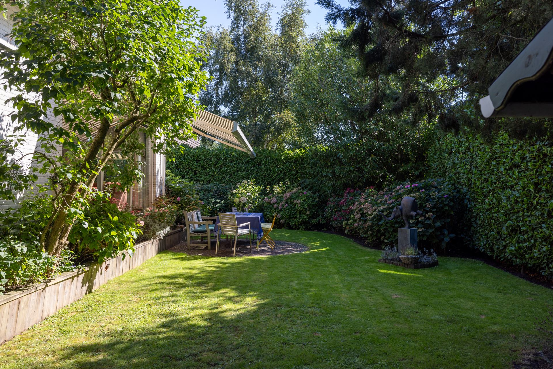 In deze romantische tuin is een grote organische plantenborder gecreëerd die mee de bocht in gaat.